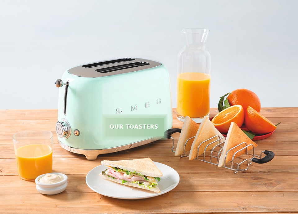 A toaster on a wooden table beside fresh oranges